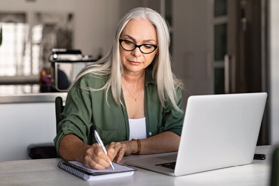 Image of a woman taking notes in front of her laptop